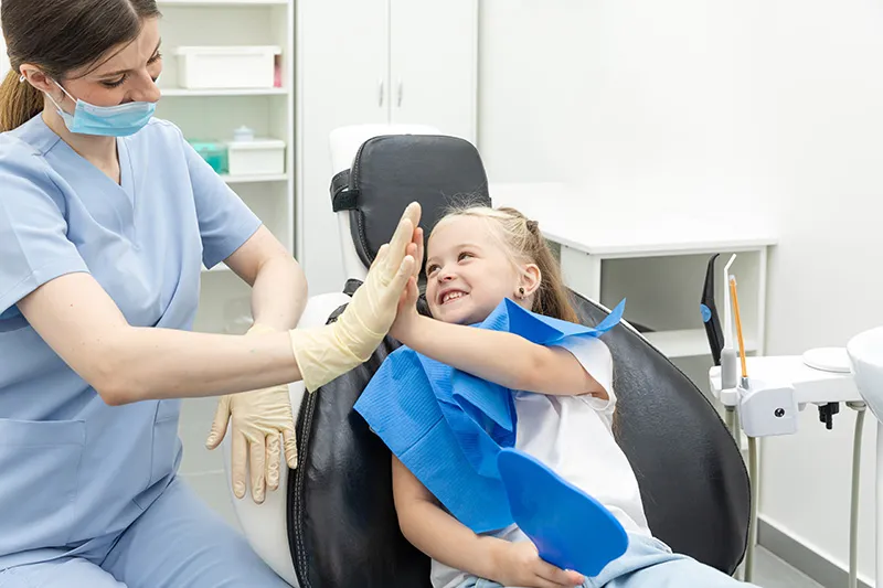 Smiling child high-fiving the dental team